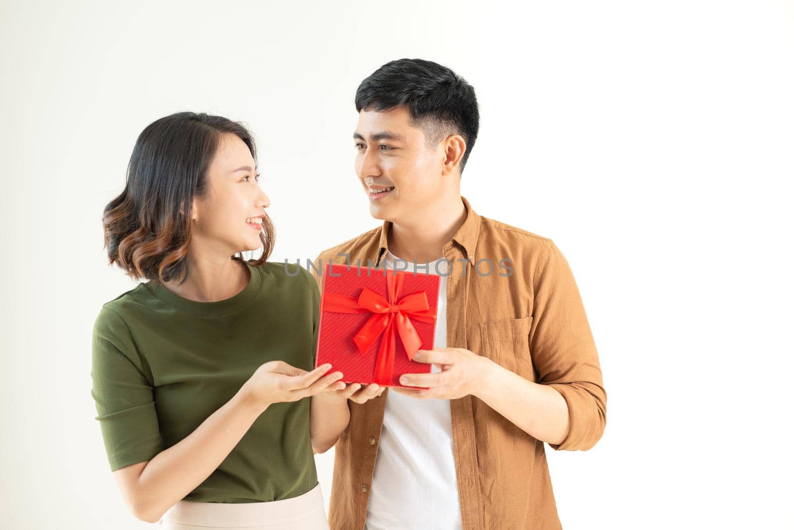 Portrait of happy couple in casual wear standing, holding box with present and looking at camera together by makidotvn