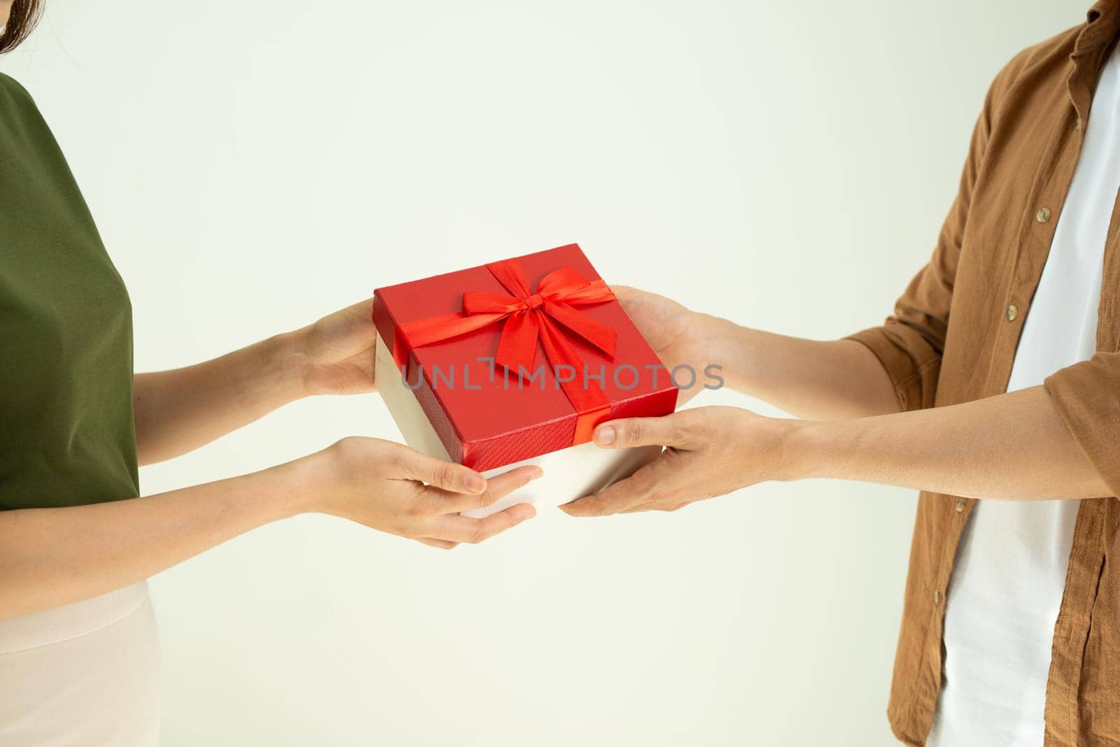 Close-up of man giving red gift box to woman over white background by makidotvn