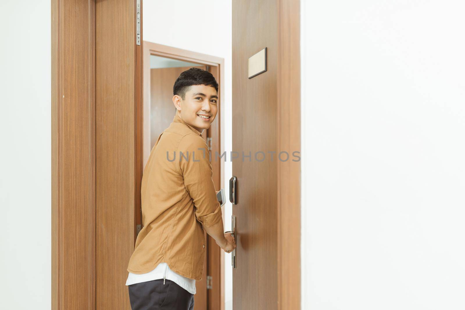 Man coming home from work and opening door of apartment