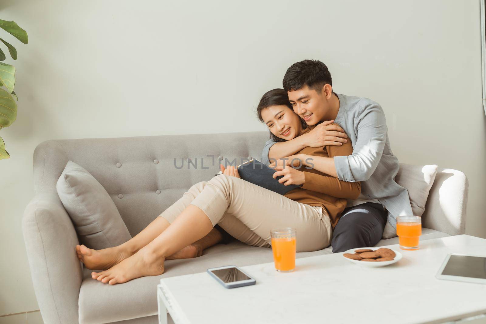 Portrait of young couple reading book sitting on couch