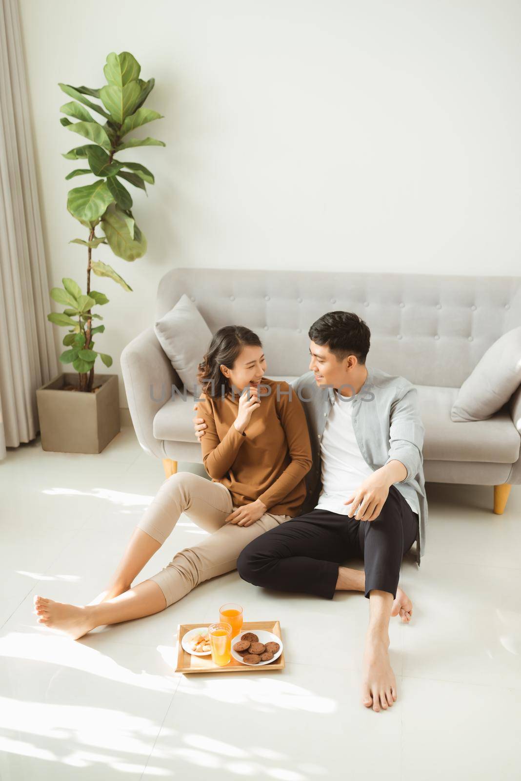 Couple sit on living room floor together eating