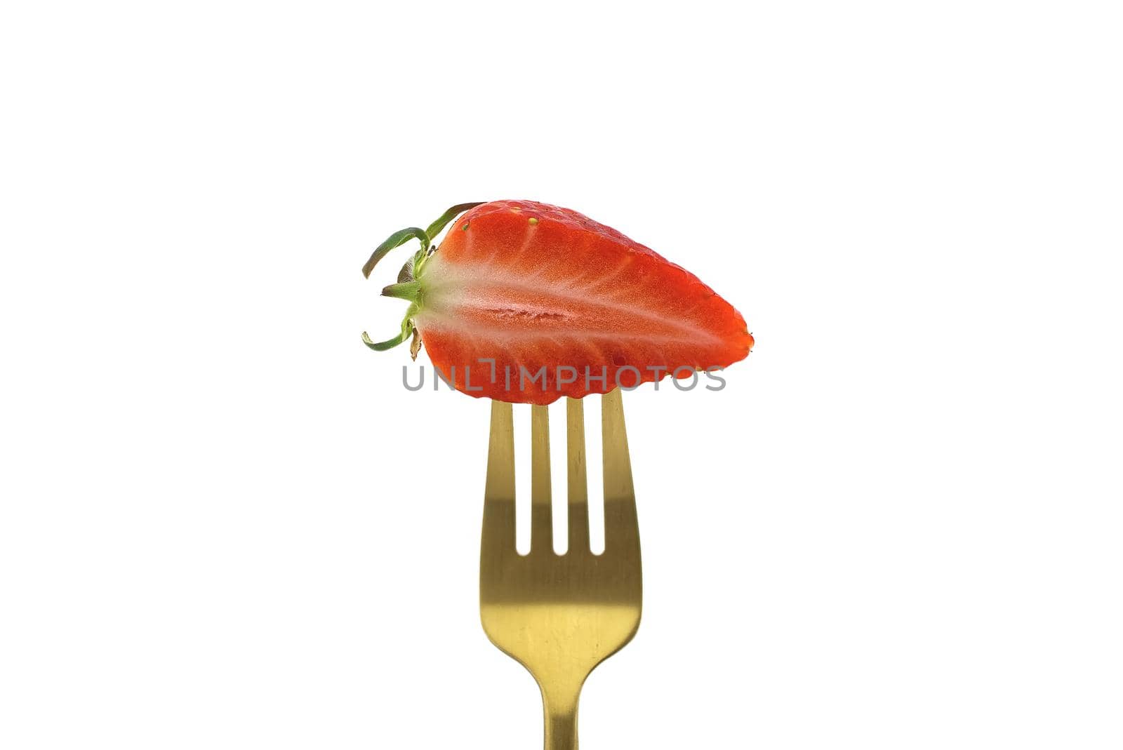 Half-cut strawberry on a golden fork isolated on a white background