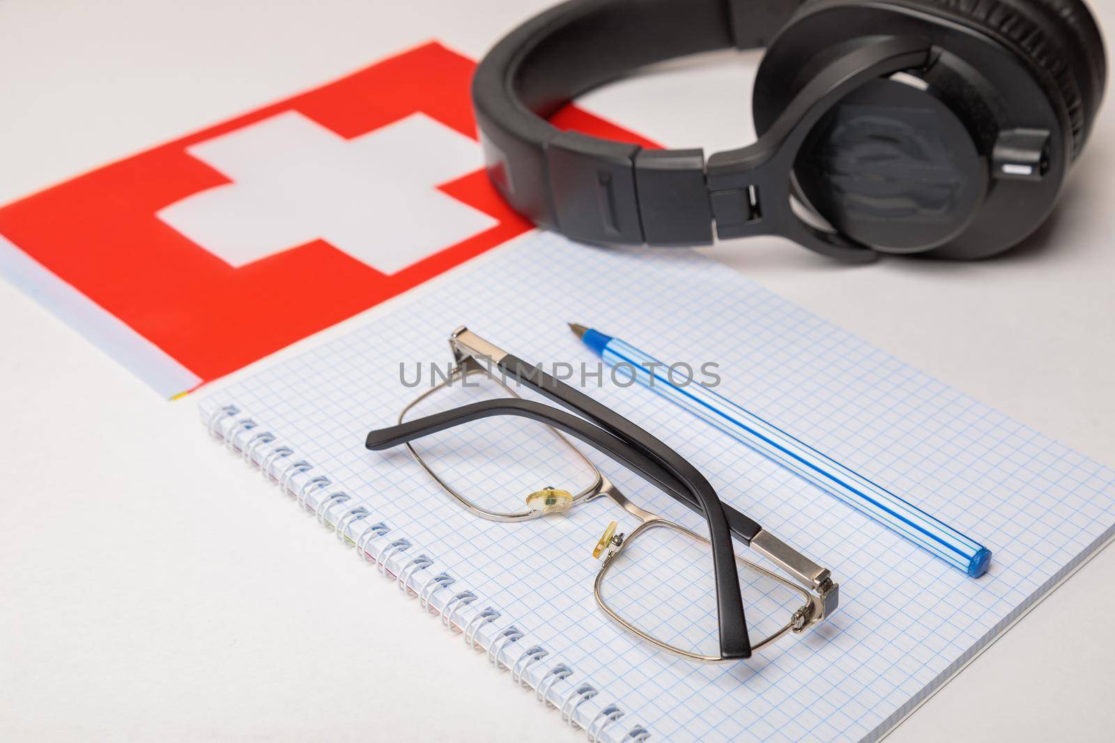 Learning foreign languages in Switzerland with audio recordings and headphones. Notepad, glasses, pen.