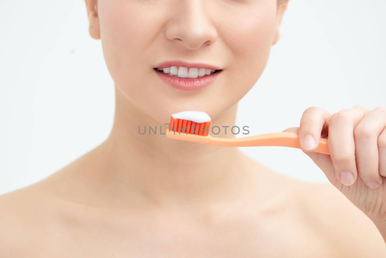 Young beautiful woman washing her perfect teeth, isolated on white background