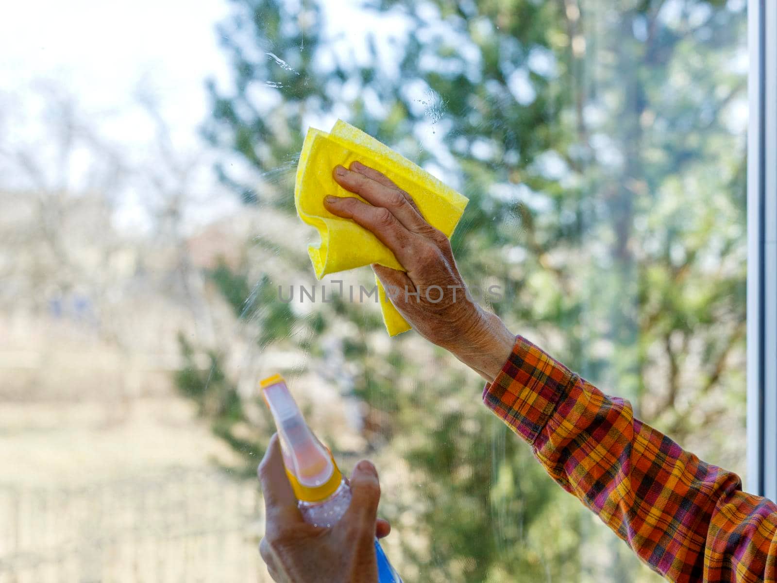 Hands with napkin cleaning window. Washing the glass on the windows with cleaning spray. Selective soft focus. Window cleaning home.