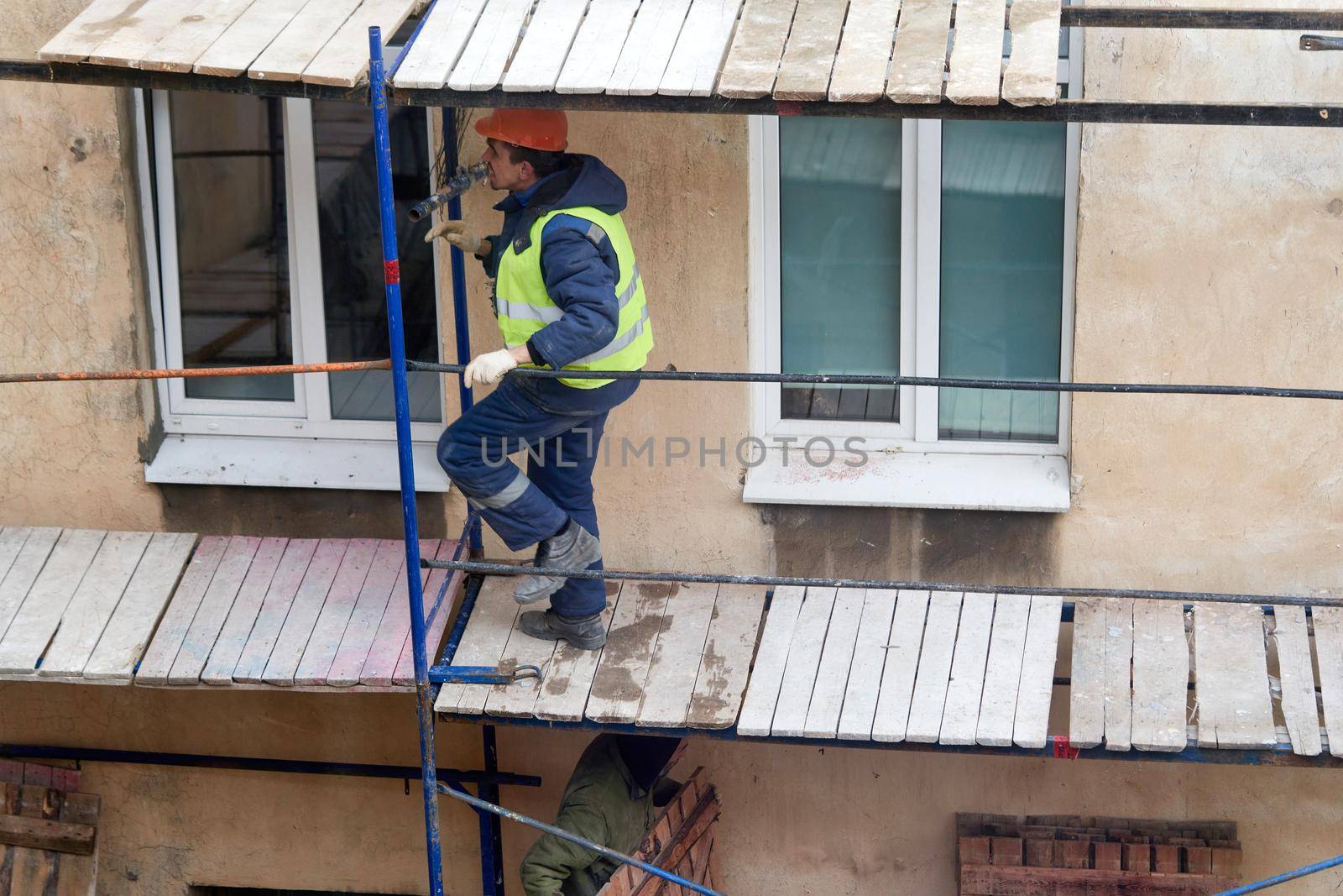 A builder installs wooden scaffolding to renovate an old house. Preparing to renovate the facade of an old house