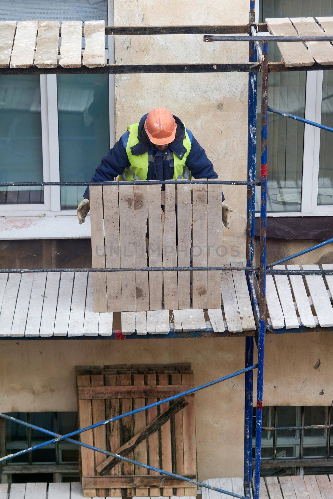 A builder installs wooden scaffolding to renovate an old house. Preparing to renovate the facade of an old house