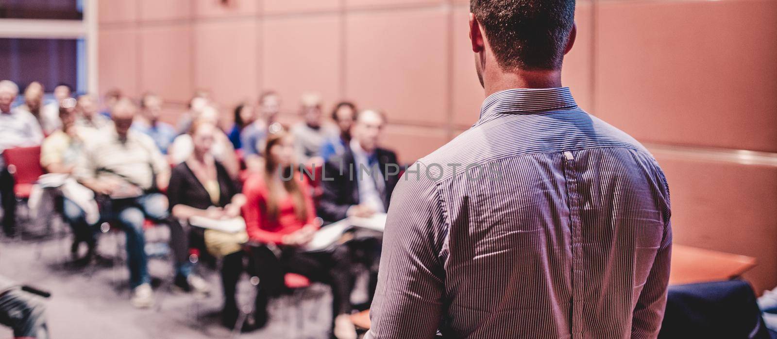 Speaker giving a talk on corporate business conference. Unrecognizable people in audience at conference hall. Business and Entrepreneurship event.