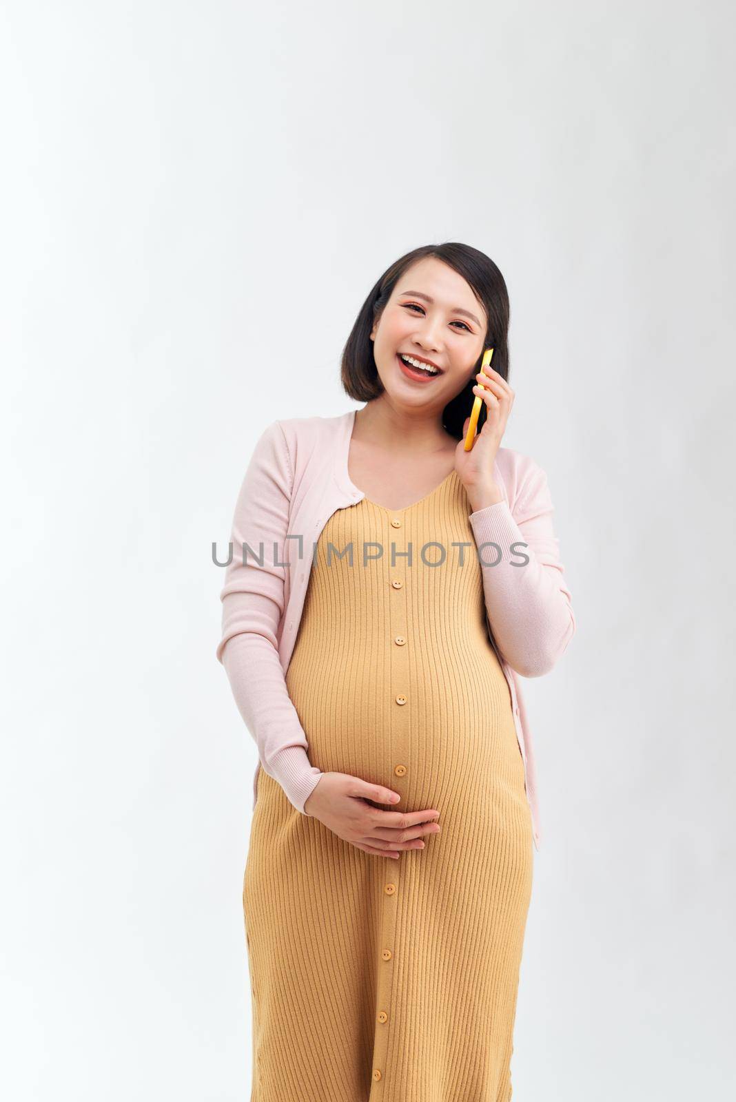 Pregnant woman talking on the phone against white background. Communication and pregnant concept.