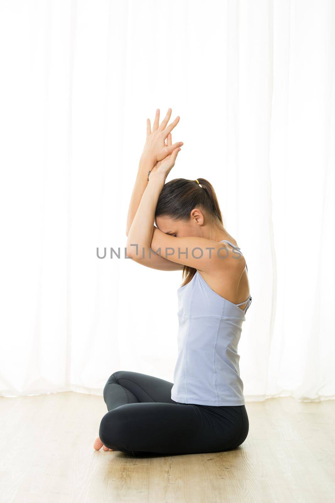 Portrait of gorgeous active sporty young woman practicing breathing exercises in yoga studio. Healthy active lifestyle, working out indoors in gym by kasto