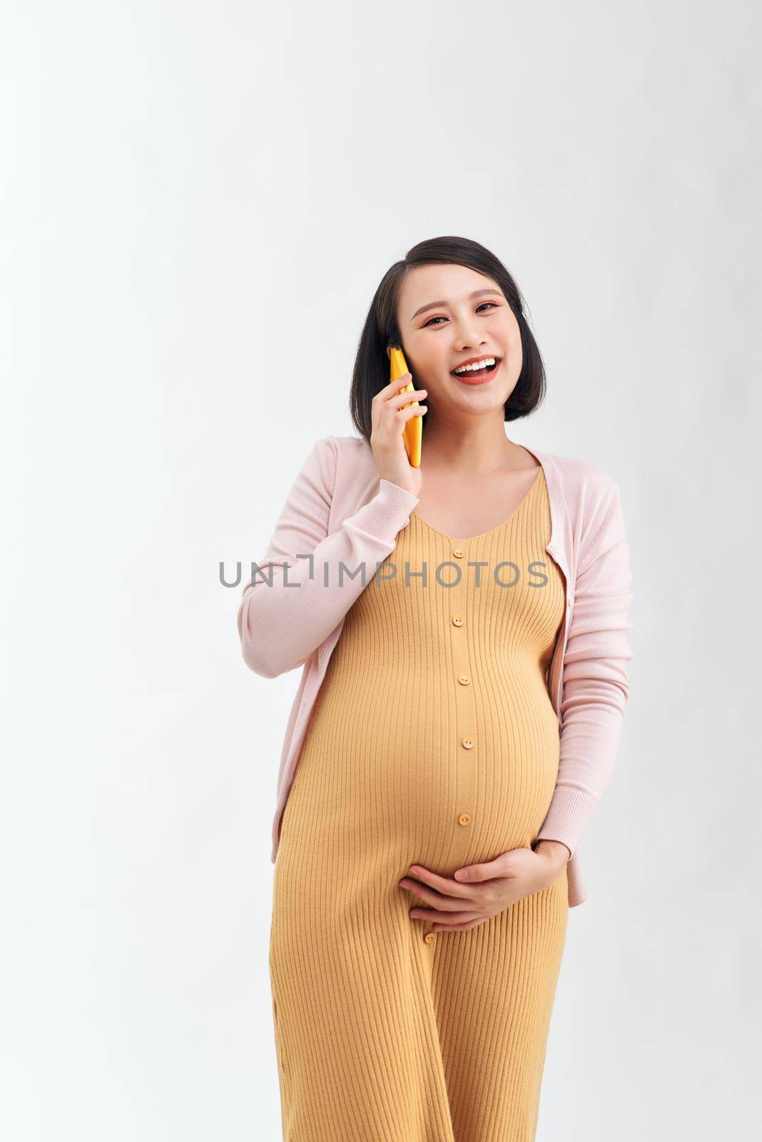 Pregnant woman talking on the phone against white background. Communication and pregnant concept. by makidotvn