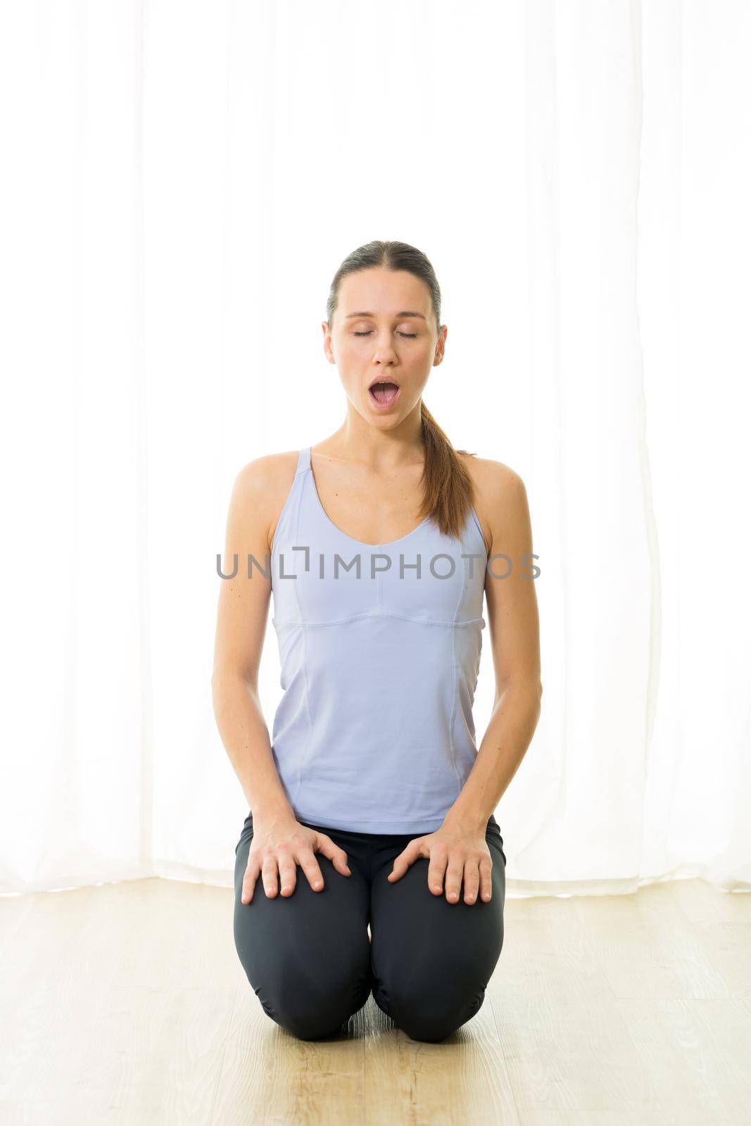 Portrait of gorgeous active sporty young woman practicing breathing exercises in yoga studio. Healthy active lifestyle, working out indoors in gym by kasto