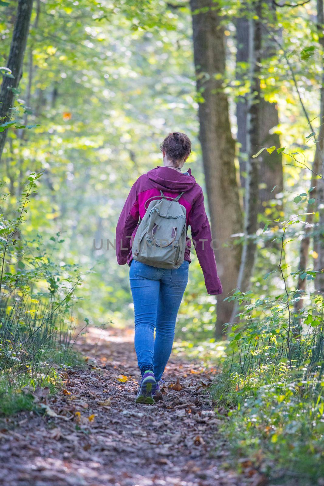 Get your mind free and forest therapy concept: Young girl is hiking through the green forest by Daxenbichler