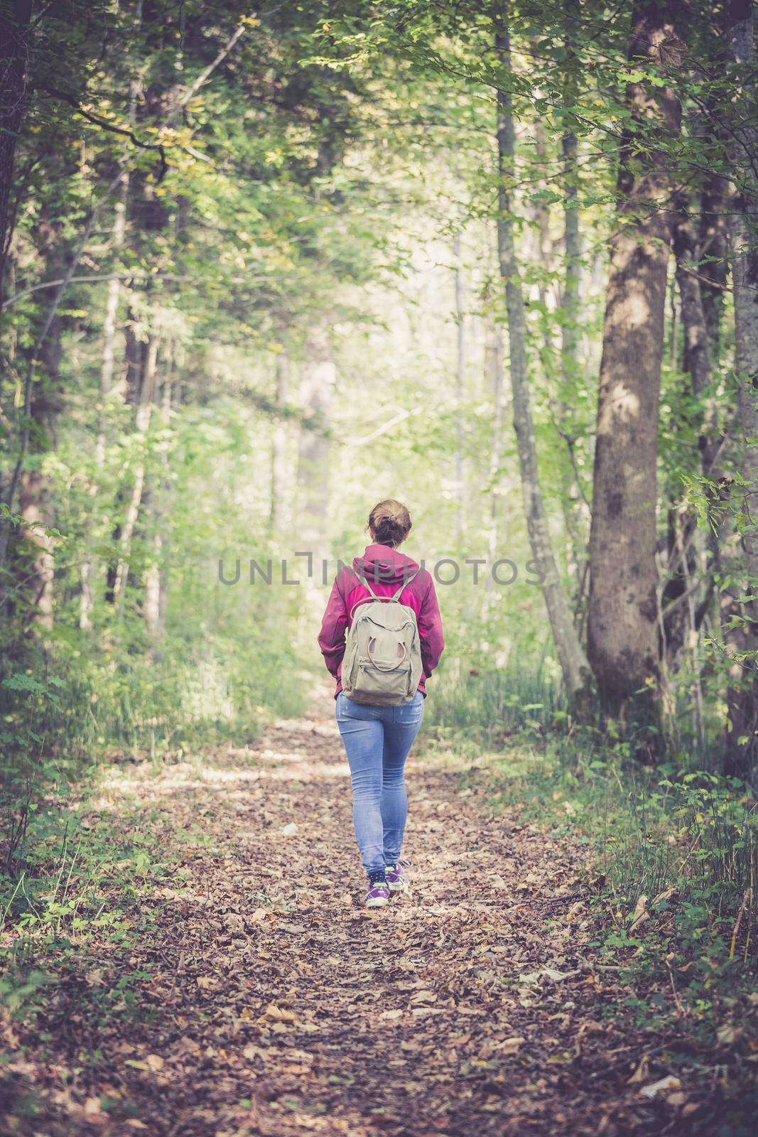 Young woman is walking through the forest, spring time