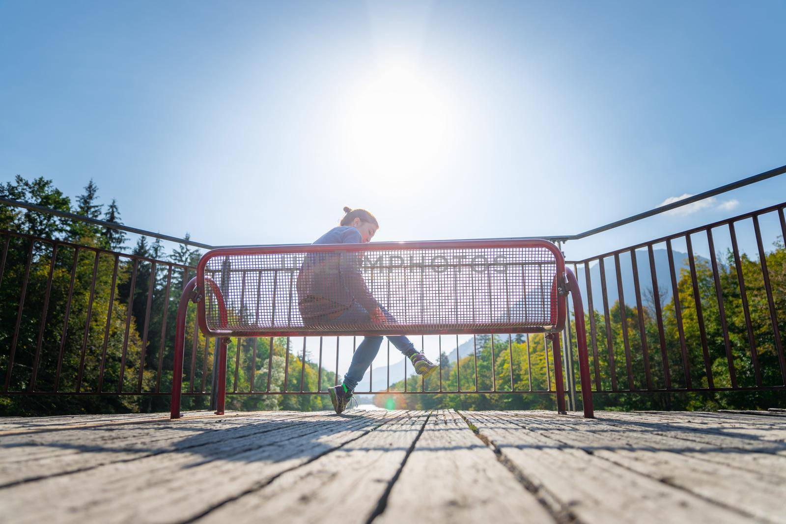 Young woman is sitting on bench, enjoying the view over a river