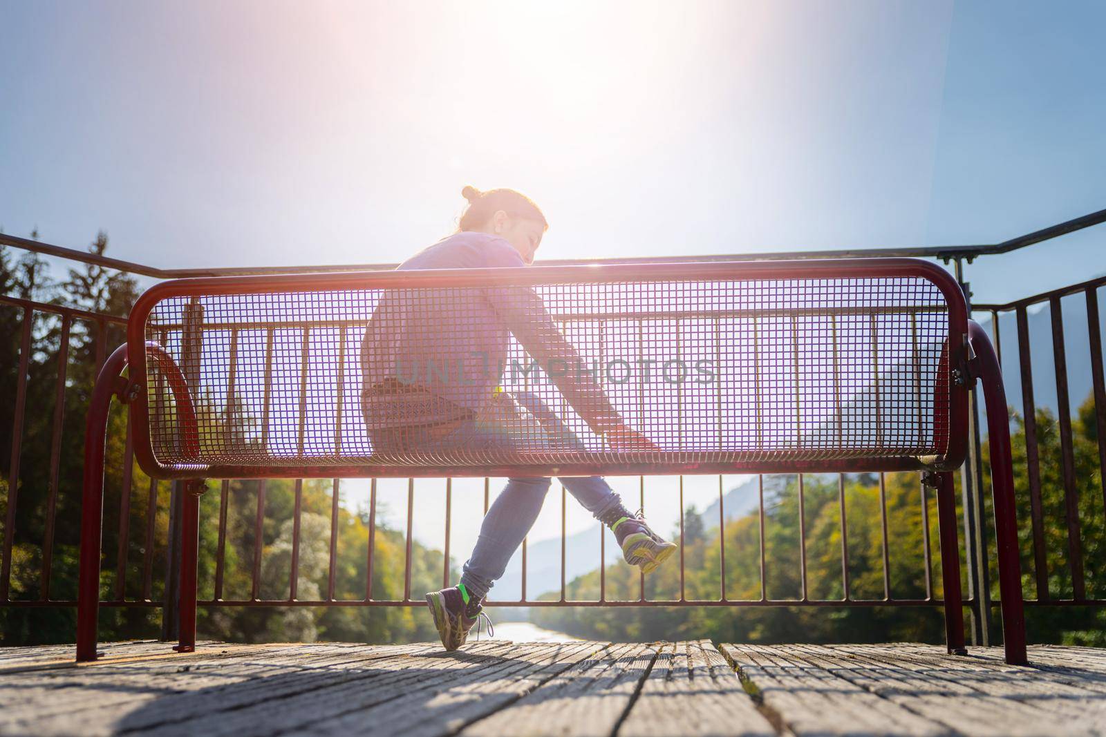 Young woman is sitting on bench, enjoying the view over a river