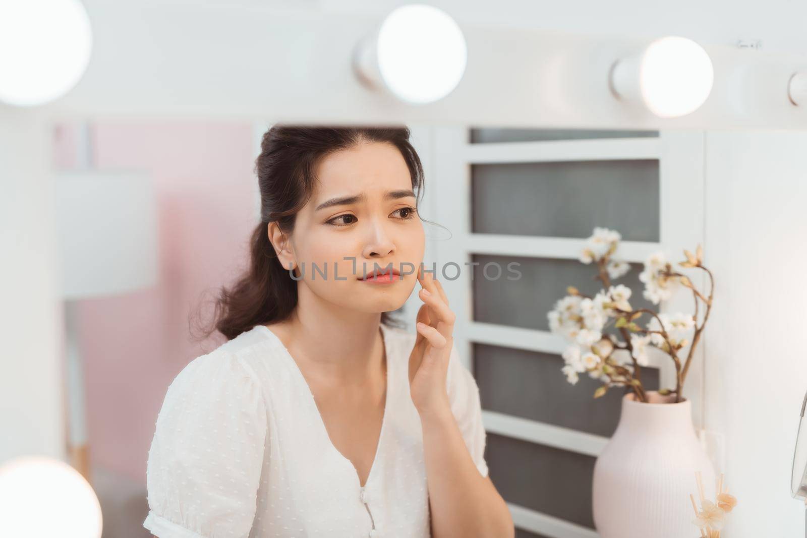 woman look mirrior feel upset and touch her face with acne problem