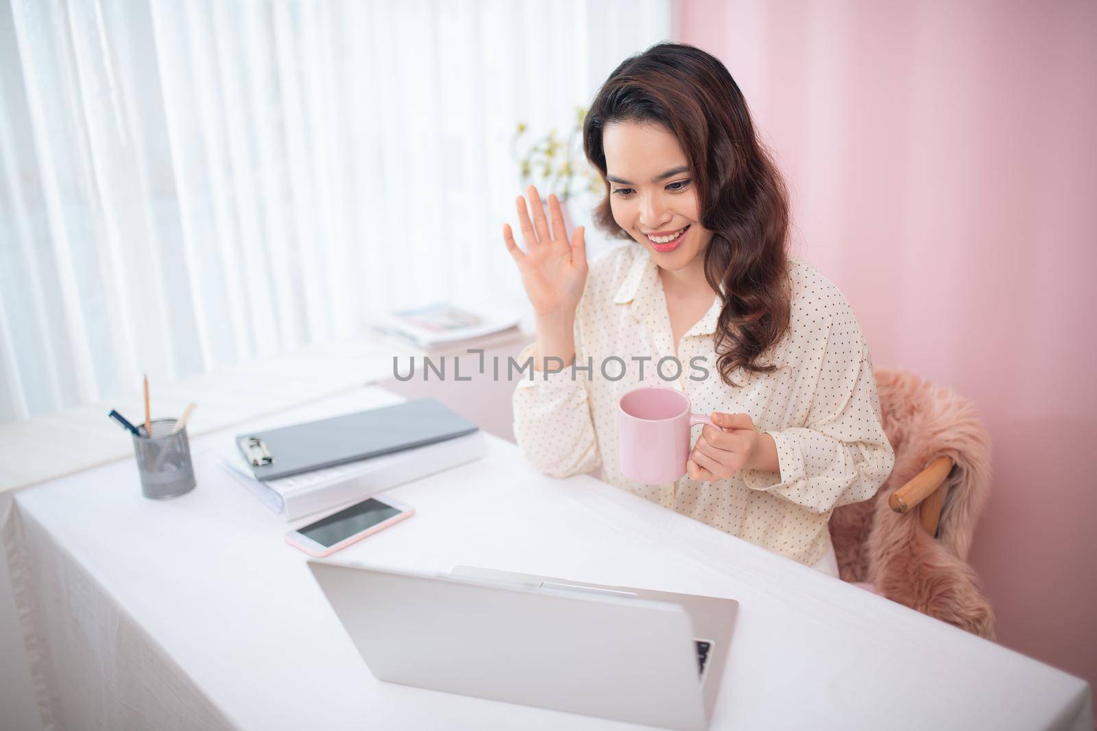 Young business woman talking to people through her laptop at her office.