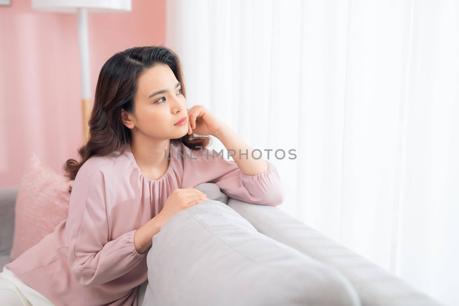 Close up young Asian woman upset when sitting at couch at home.