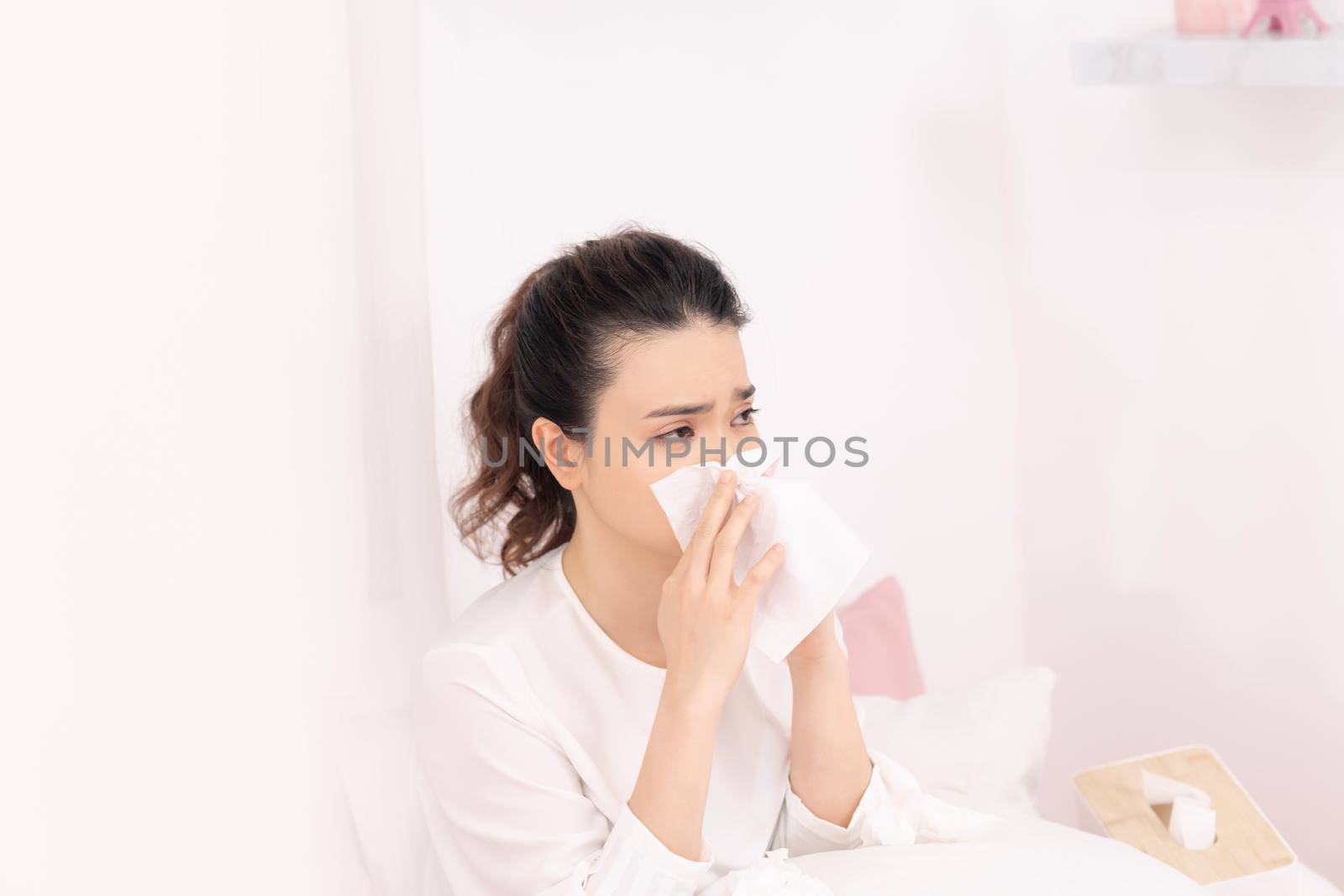 Sick woman with headache sitting under the blanket. Sick woman with seasonal infections, flu, allergy lying in bed