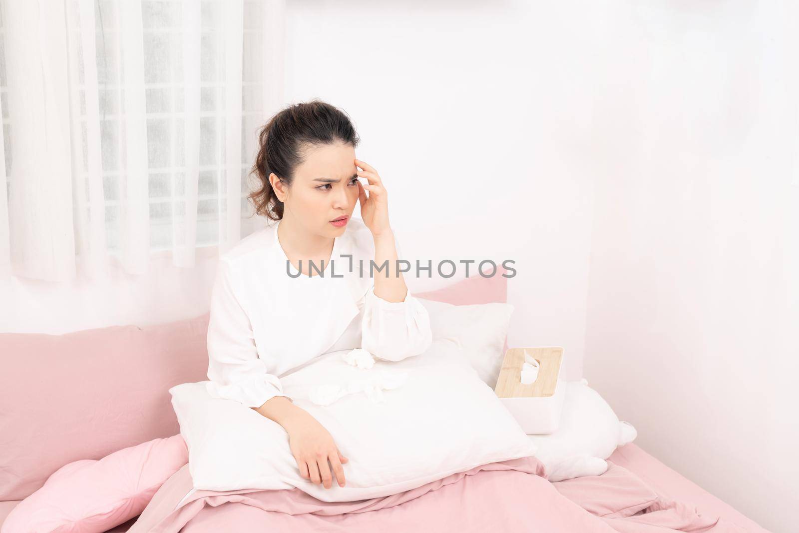 Flu. Closeup image of frustrated sick woman with red nose lying in bed in thick scarf