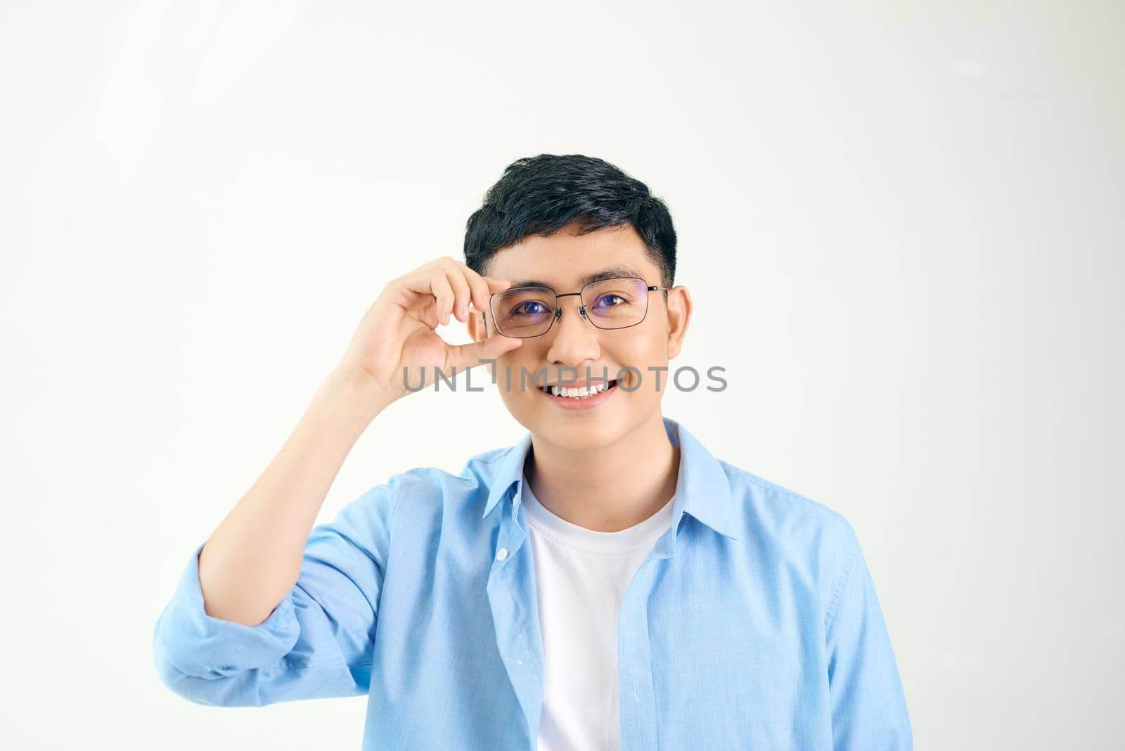 Closeup of friendly guy wearing eyeglasses. Young asian man adjusting glasses and staring at camera through lens. Vision and eye care concept