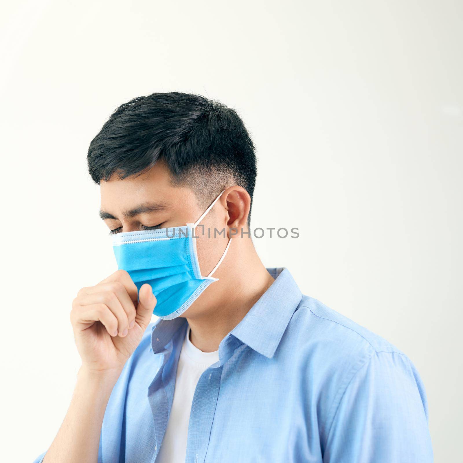 Asian man wearing surgical face mask coughing in subway station with crowded people walking pass. Wuhan coronavirus (COVID-19) outbreak prevention