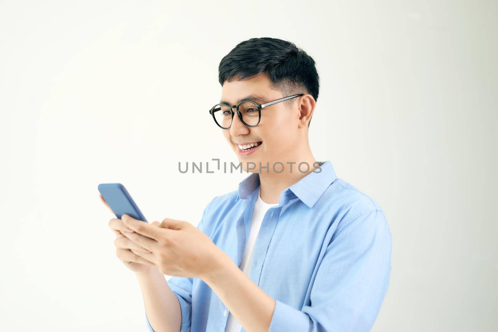 Relaxed young casual man reading text message on mobile phone isolated over white by makidotvn