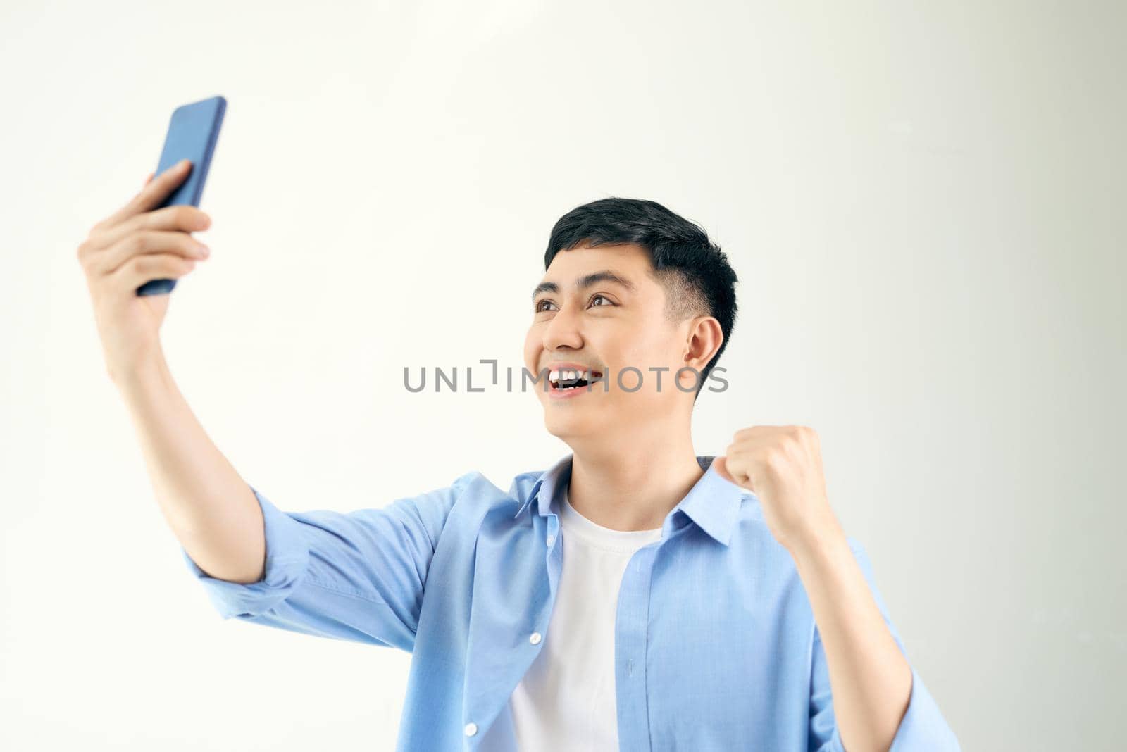Handsome smiling man is standing, holding telephone and taking a selfie