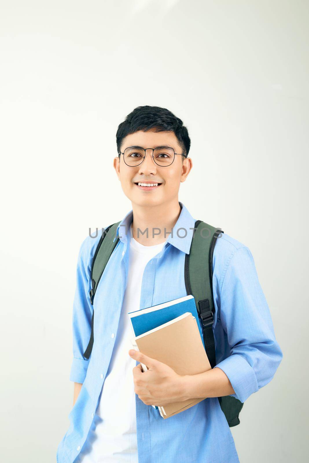 Handsome young student smiling and holding a notebook, isolated on white background