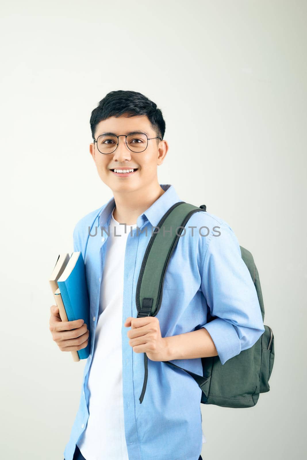 Handsome happy student smiling and a backpack and notebooks on white background