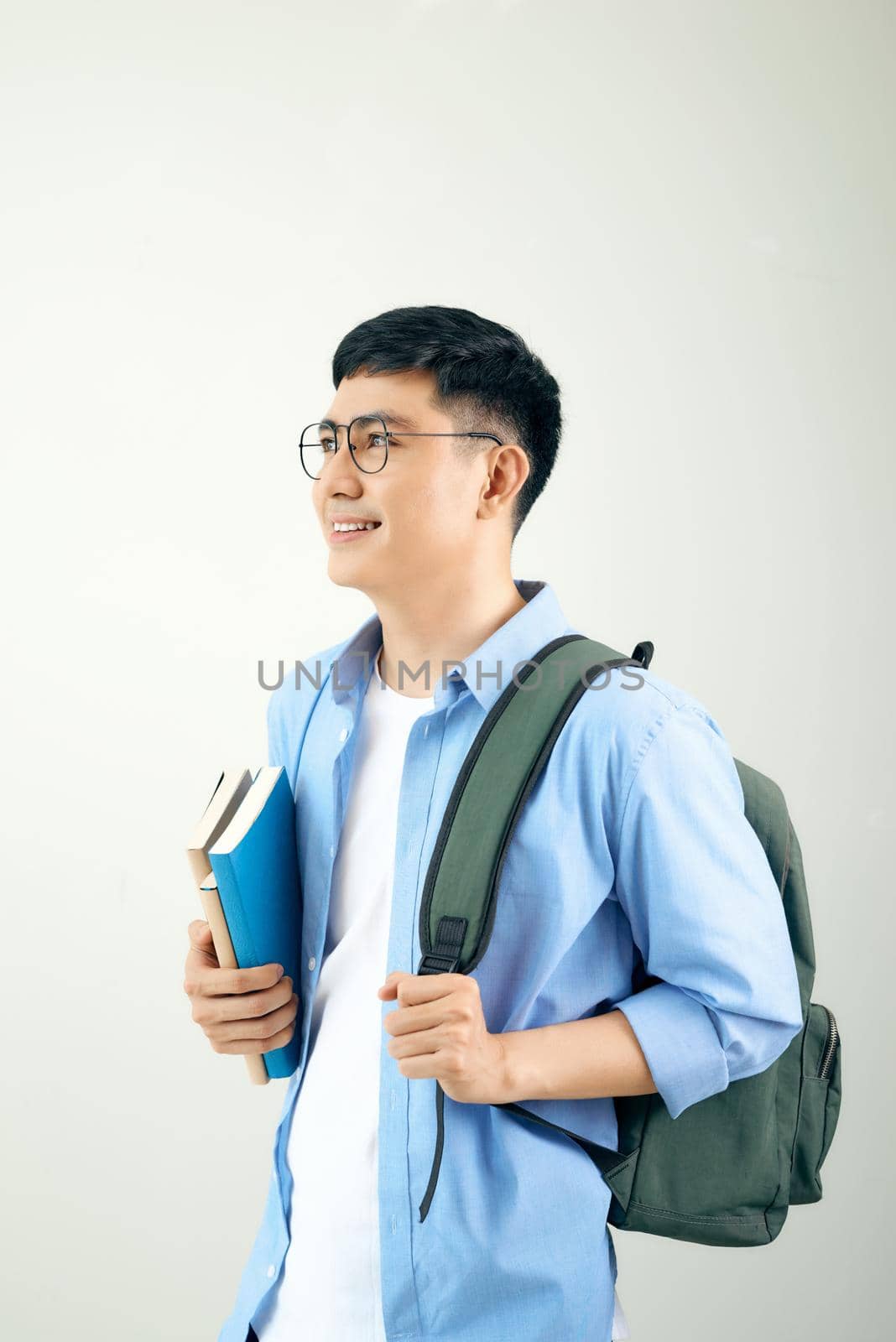 A smiling student carrying his backpack, isolated on a white background