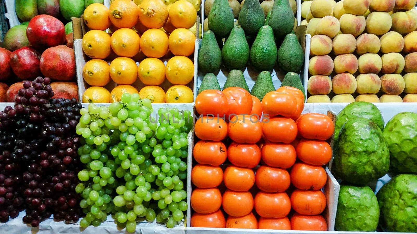 Assortment of fresh fruits and vegetables on market counter in a wooden boxes