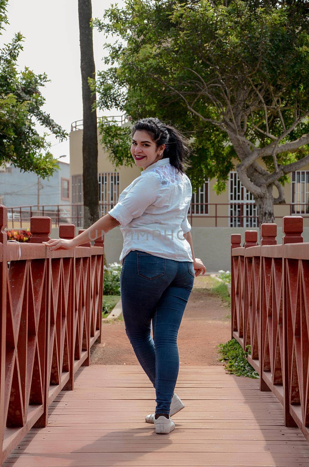 Very pretty plump woman standing on a bridge looking at the camera