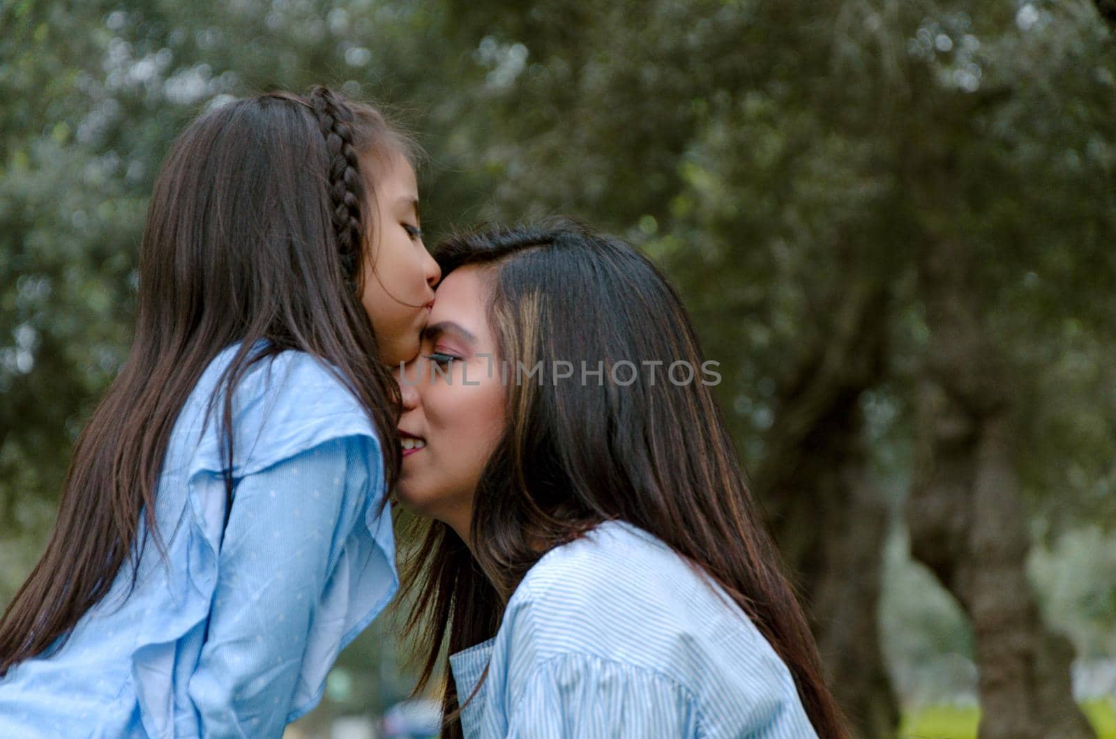 Happy daughter kissing her mother enjoying a winter afternoon in the park