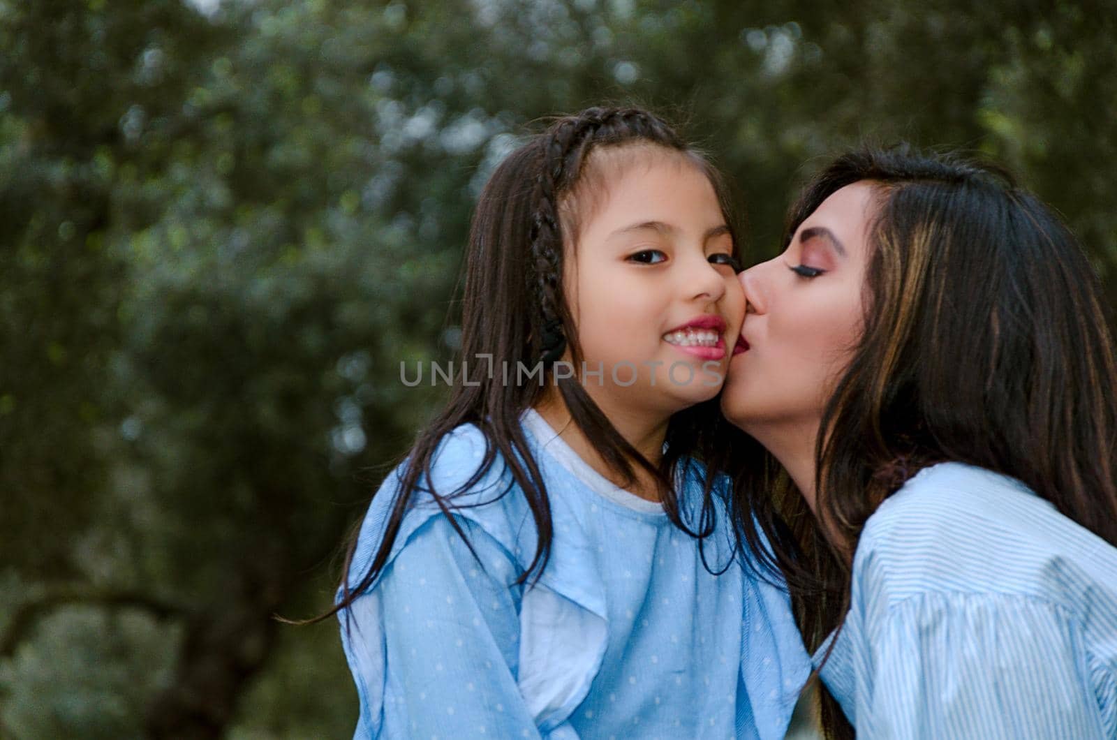 Happy mother kissing her daughter enjoying a winter afternoon in the park