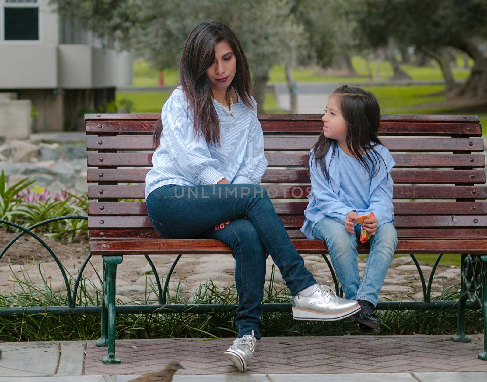 Mother and her little daughter sitting on a bench in the park