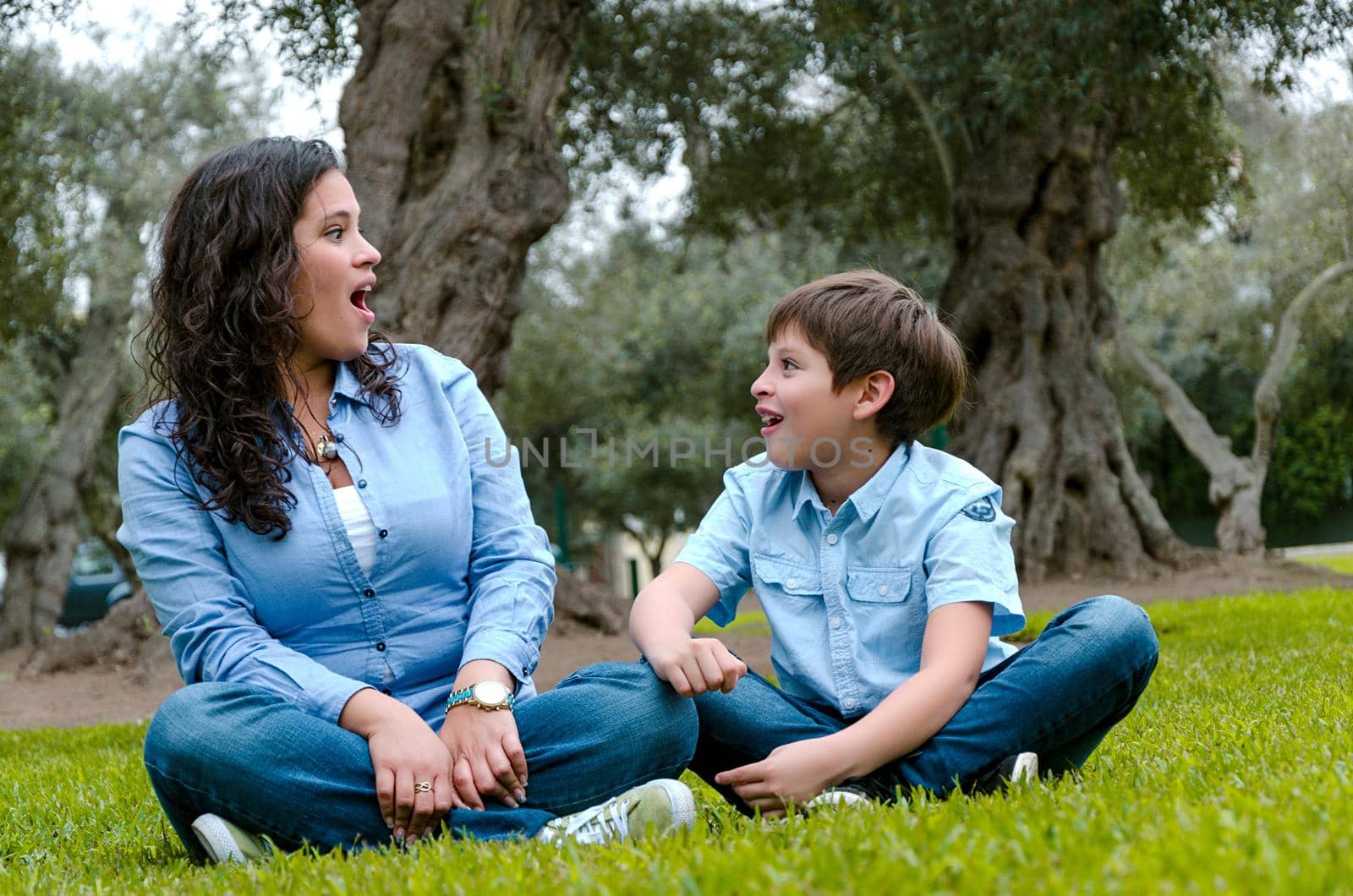 Beautiful woman and her cute little son looking to each other amazed in the park