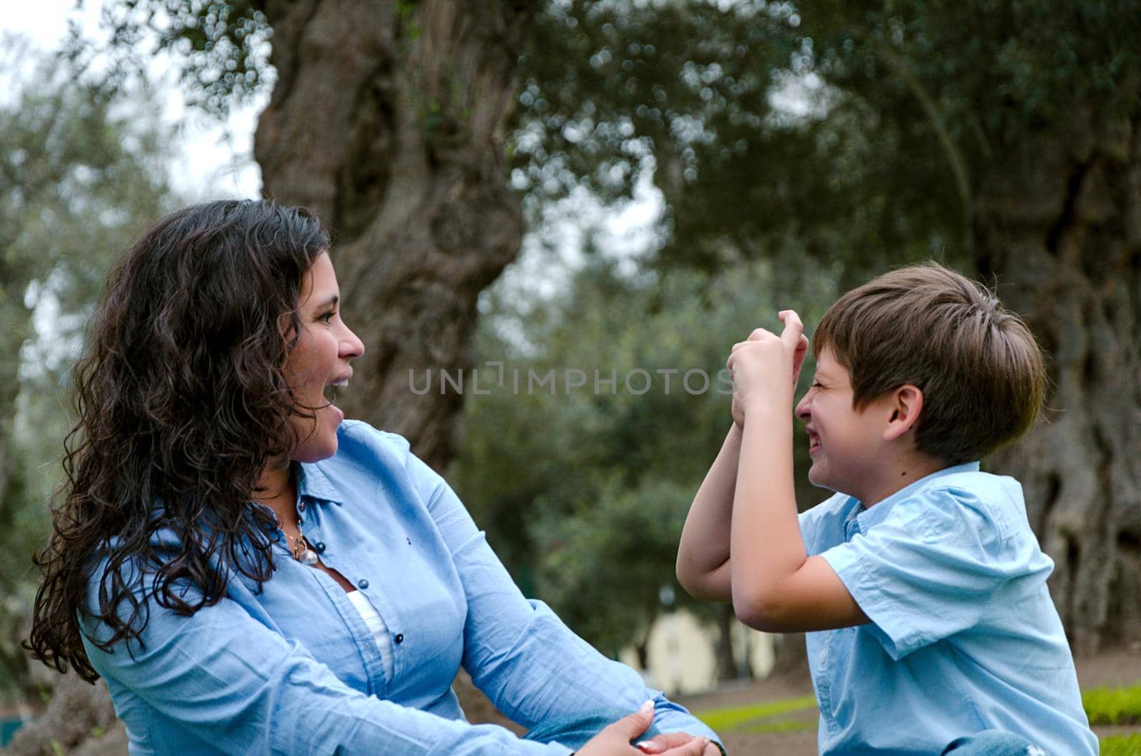 Beautiful woman and her cute little son looking at each other, son making the mimic of taking picture of the mother, the concept of wanting to take a picture