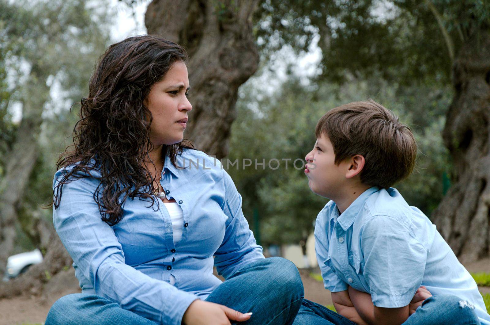 Portrait of a mother scolding to her son sitting on the grass by Peruphotoart