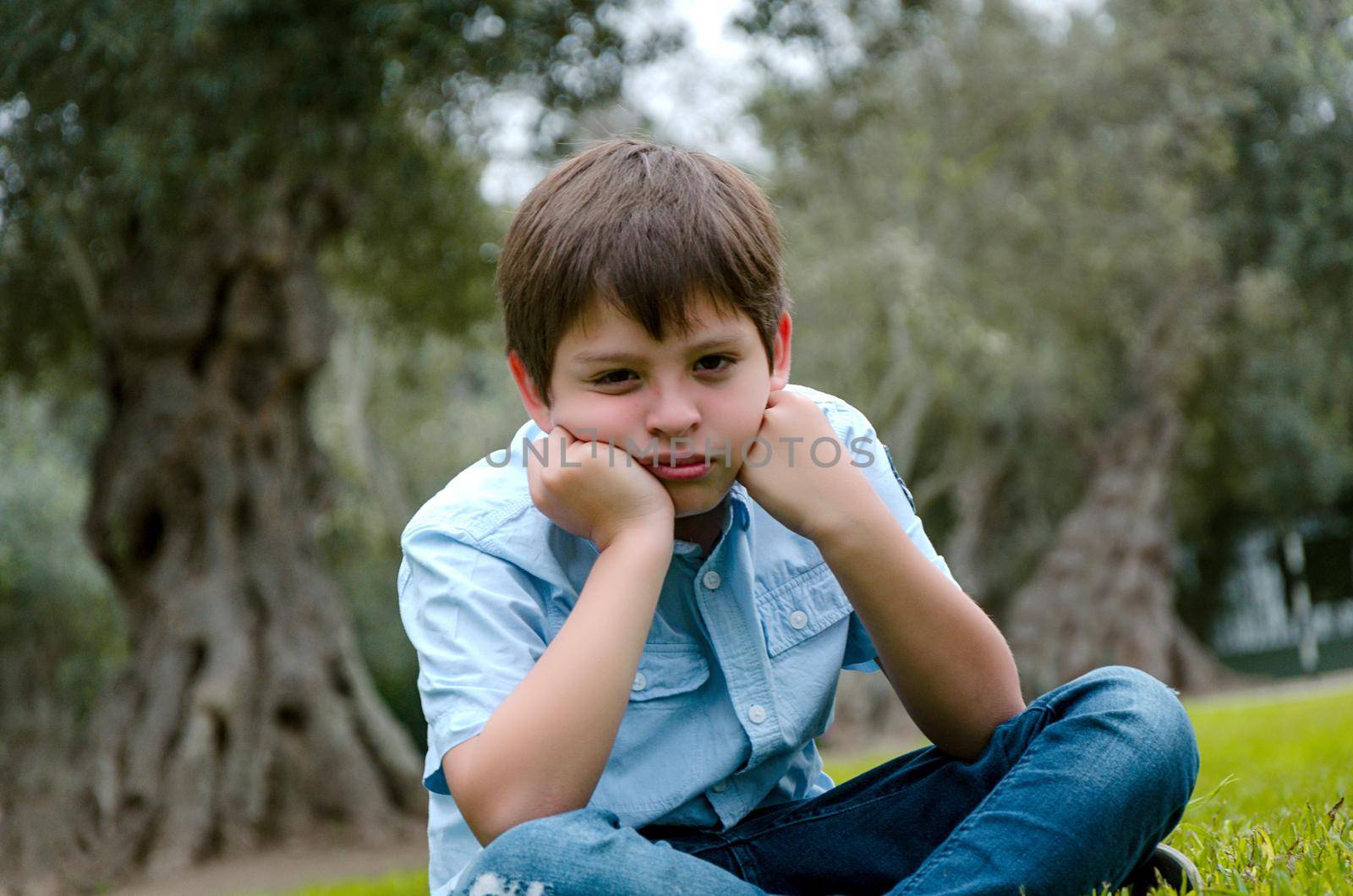 Toddler boy with funny face sad or bored .he sitting alone at park on autumn day