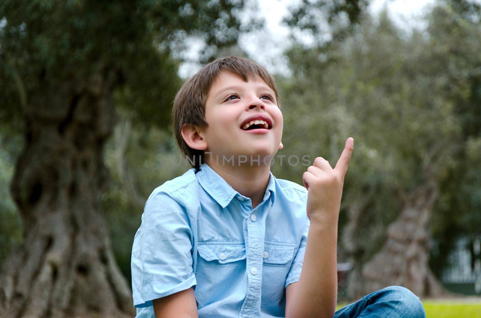 Portrait child with blond hair has an idea, pointing with finger up looking up