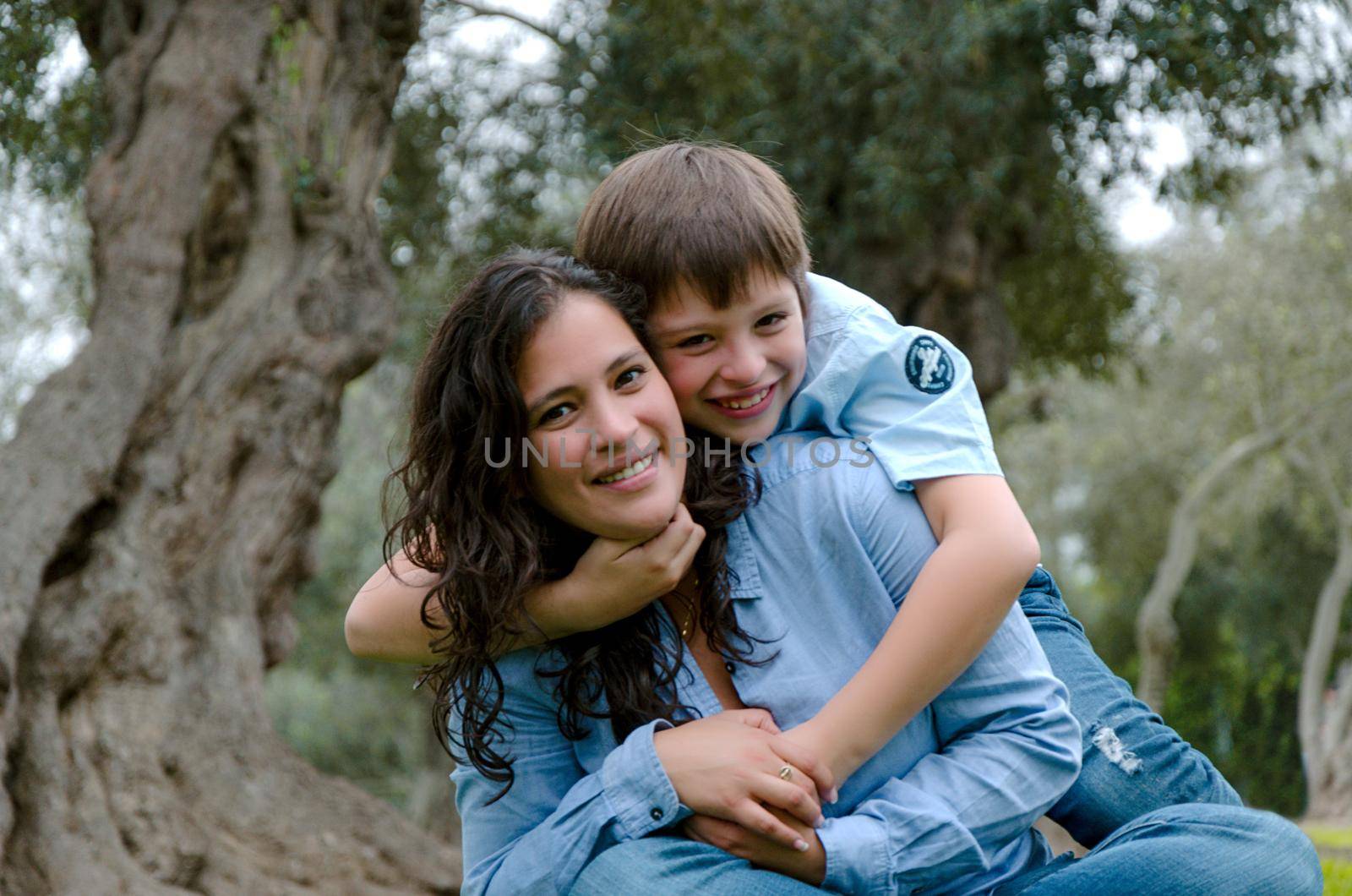 Child hugging his mother smiling on an autumn afternoon in the park