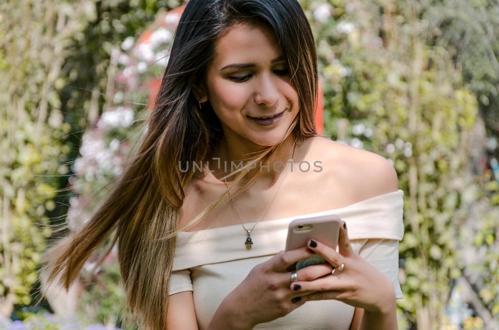 Happy girl watching media in a smartphone sitting on a bench of a city park