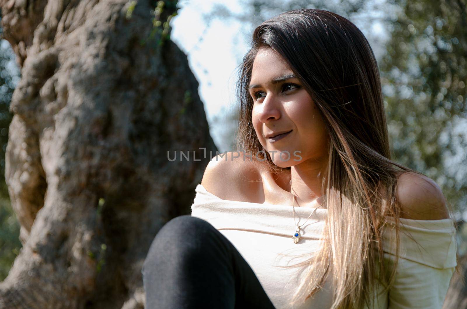 Beautiful smiling teenage girl, against green of summer park.