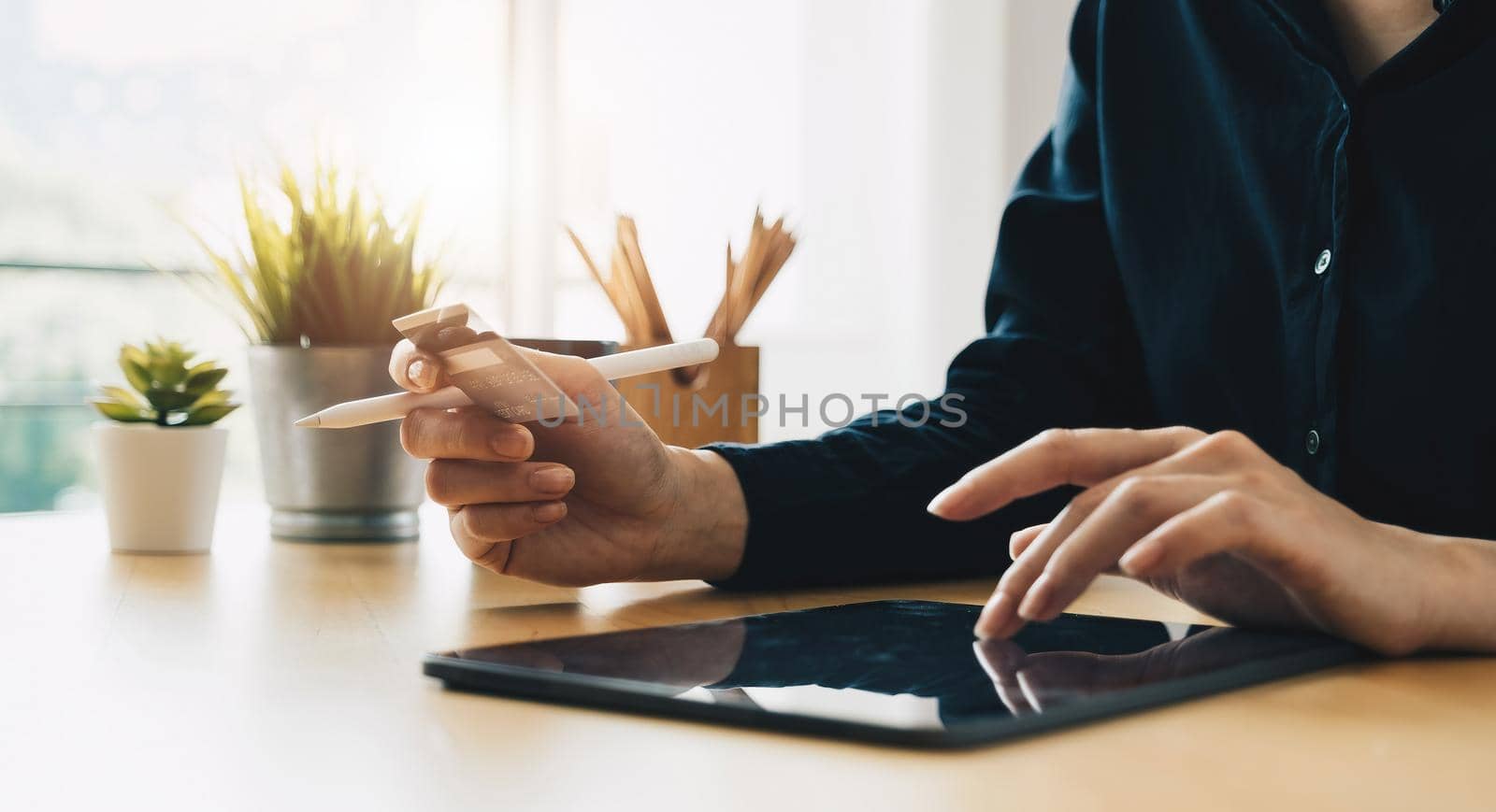 Woman's hands holding a credit card and using digital tablet for online shopping at home.