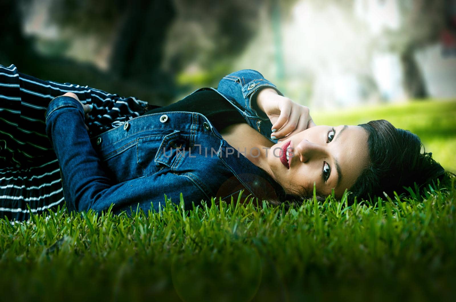 Cute young brunette reclining on the grass in the park enjoying a summer day