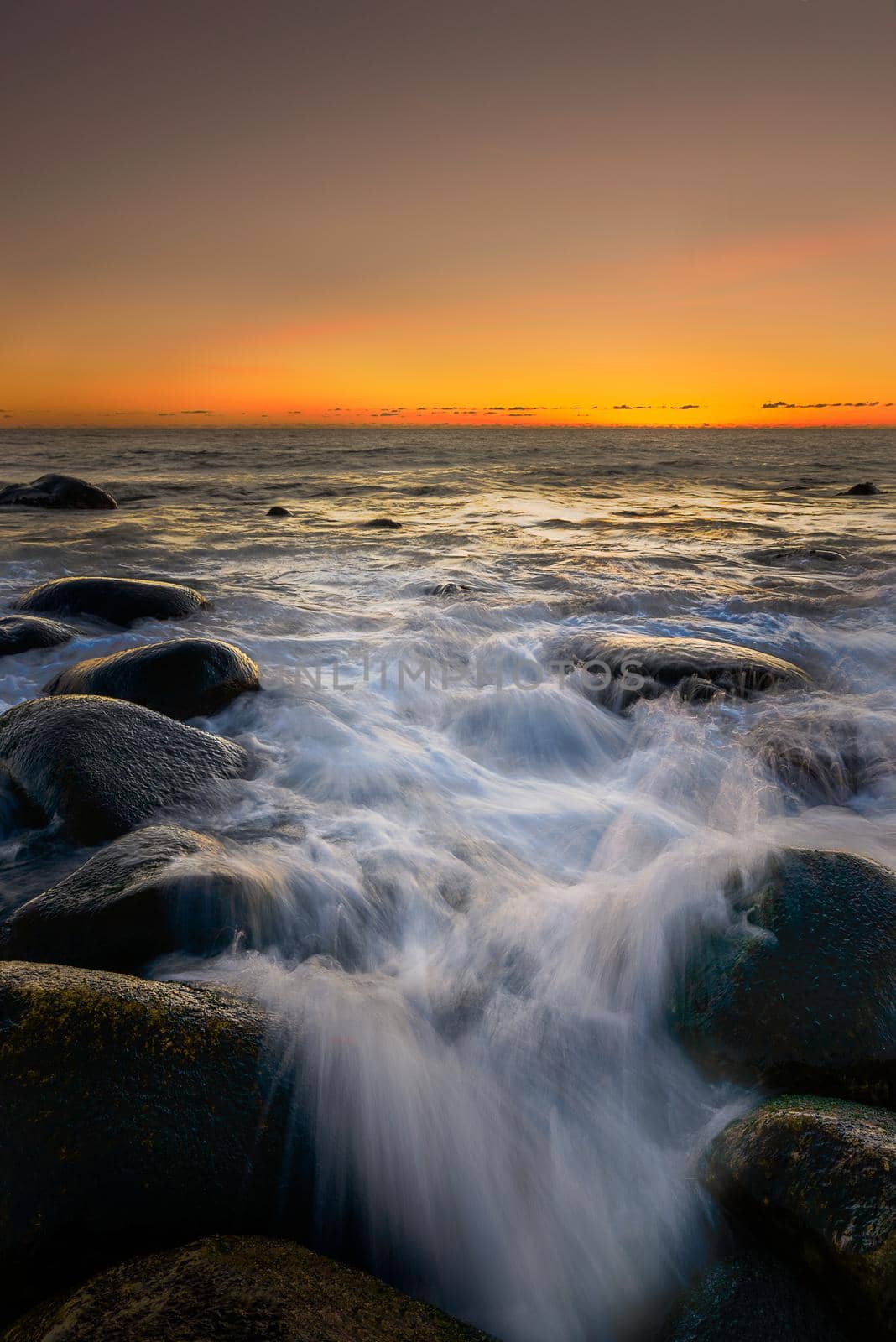 Long exposure shot of water washing in over rocks at the coastline.