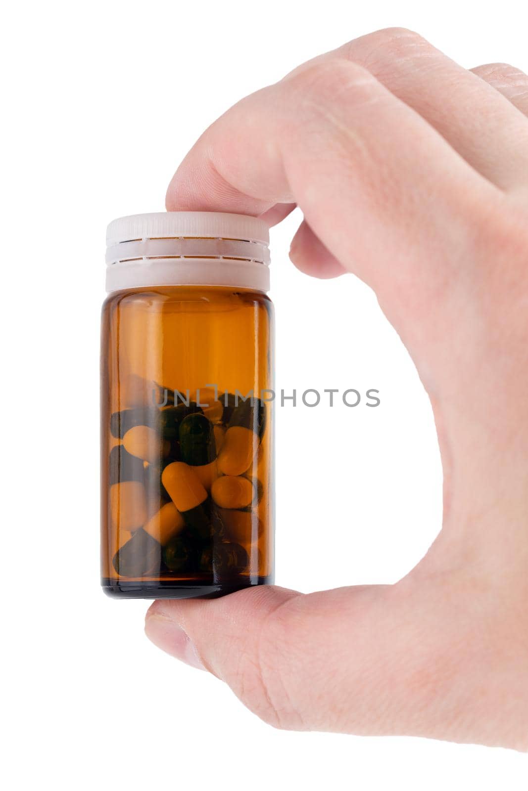 caucasian hand holding brown glass bottle with medical pills inside.