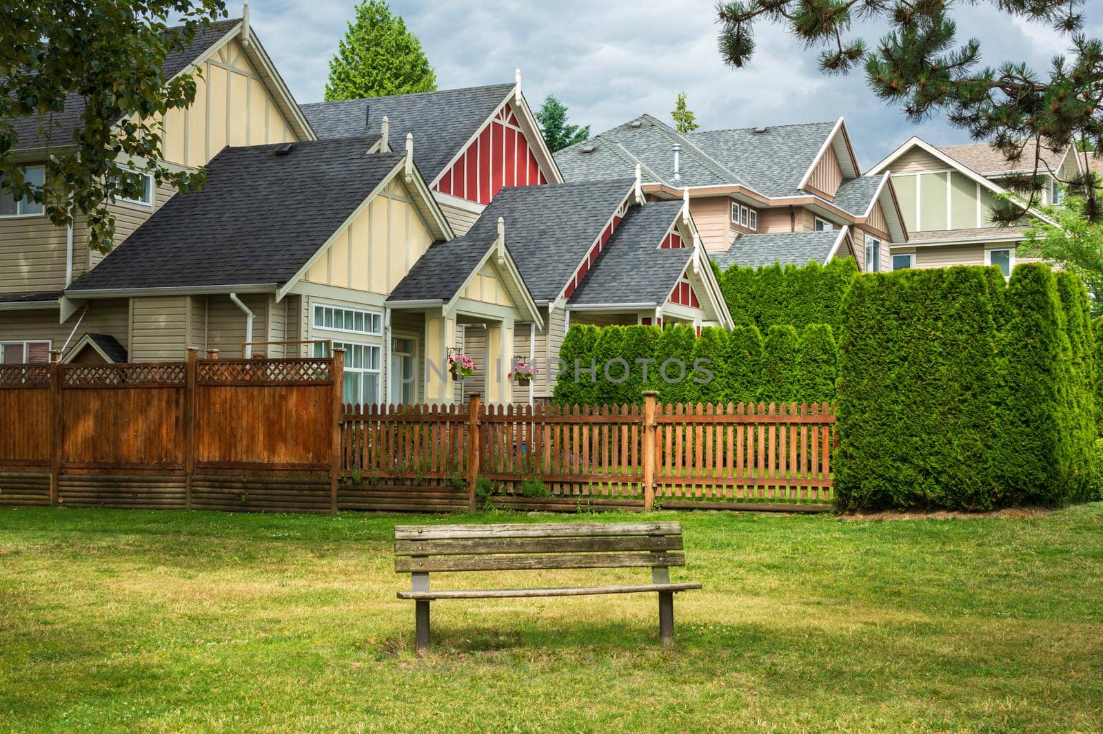 Old wooden bench in a park are in front of residential houses.